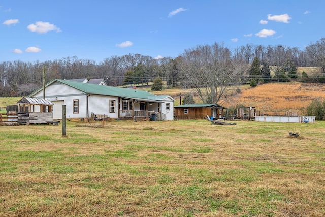 view of yard with a porch, an outdoor structure, and a swimming pool