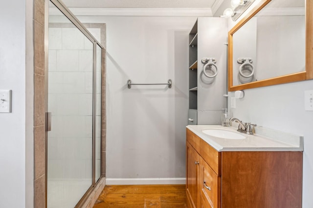 bathroom featuring walk in shower, crown molding, vanity, and hardwood / wood-style flooring