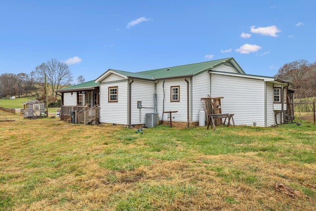 rear view of house with central AC and a lawn