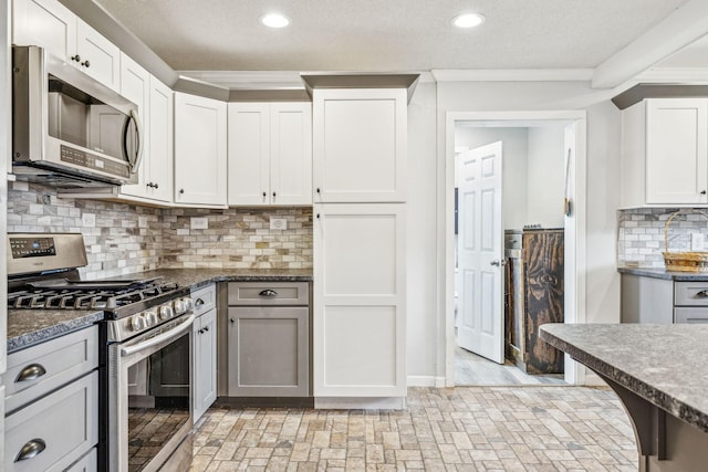 kitchen with white cabinets, a textured ceiling, stainless steel appliances, and crown molding