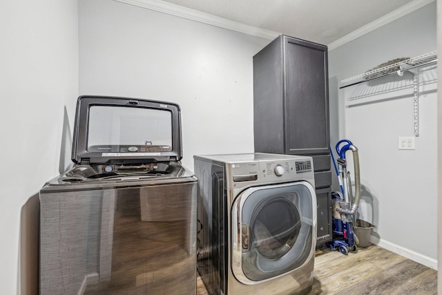 laundry area featuring washing machine and dryer, light hardwood / wood-style flooring, and crown molding