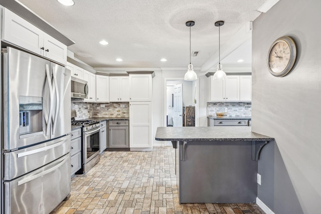 kitchen with backsplash, a kitchen breakfast bar, kitchen peninsula, white cabinetry, and stainless steel appliances