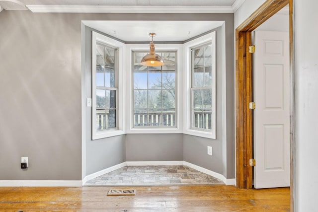 unfurnished dining area with light hardwood / wood-style floors and ornamental molding