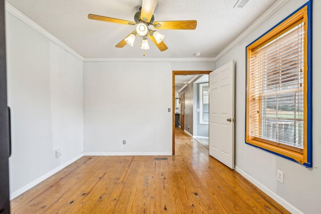 spare room featuring a textured ceiling, ceiling fan, light wood-type flooring, and crown molding