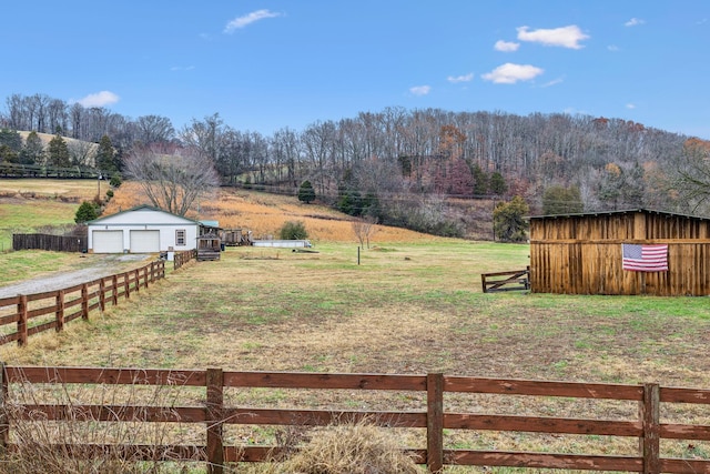 view of yard featuring a rural view, a garage, and an outdoor structure