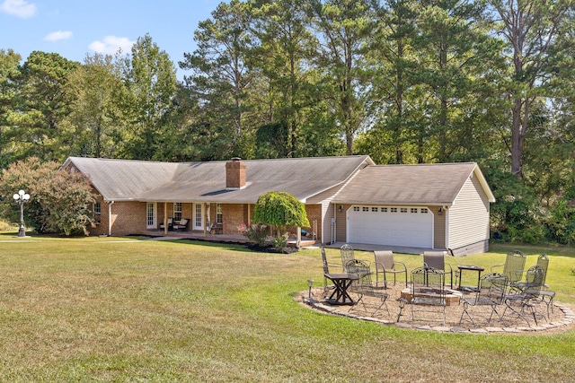 ranch-style home with covered porch, a garage, a front yard, and an outdoor fire pit