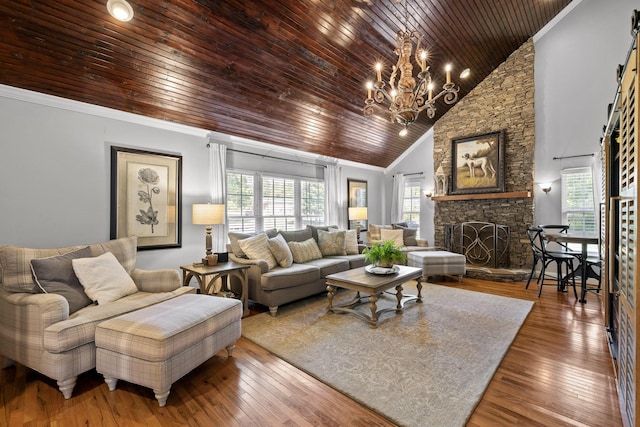 living room featuring ornamental molding, hardwood / wood-style flooring, high vaulted ceiling, a notable chandelier, and a fireplace