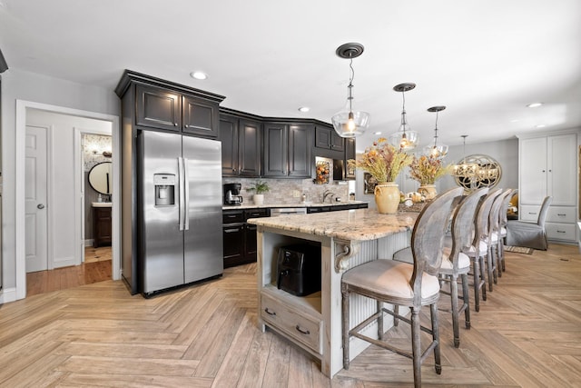 kitchen with light stone countertops, light parquet floors, decorative light fixtures, and stainless steel refrigerator with ice dispenser