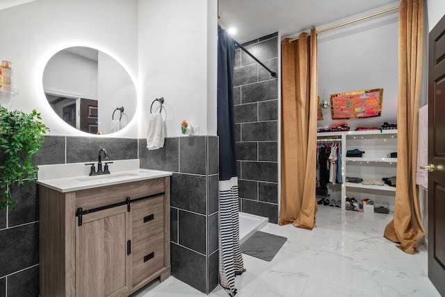 bathroom featuring a shower, vanity, and tile walls