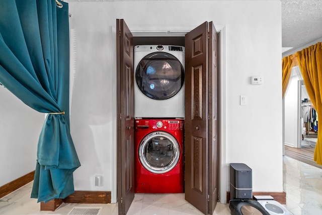 washroom featuring a textured ceiling and stacked washer and clothes dryer