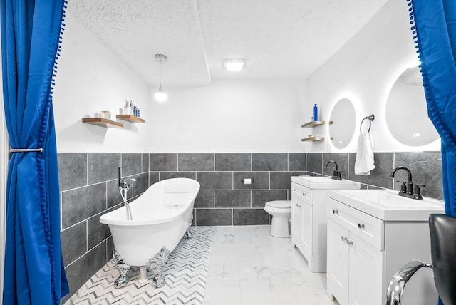 bathroom with vanity, a textured ceiling, a bath, tile walls, and toilet