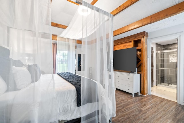 bedroom with beam ceiling, ensuite bath, and dark hardwood / wood-style floors