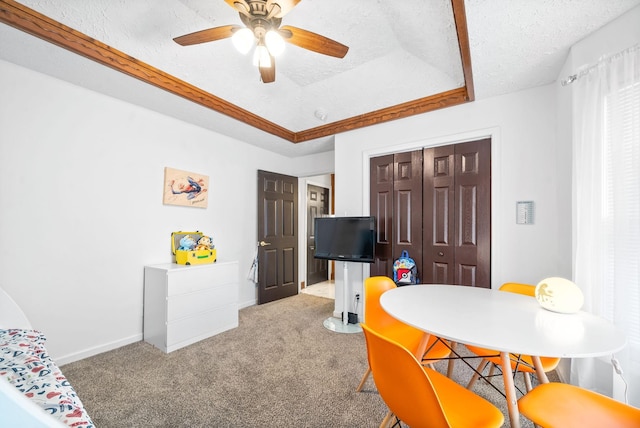 dining room featuring a raised ceiling, ceiling fan, carpet, and a textured ceiling