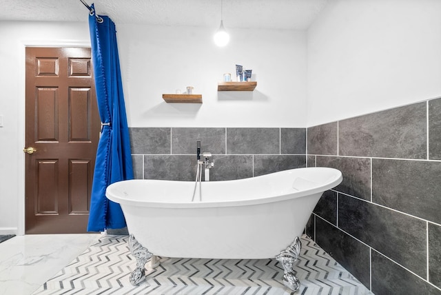 bathroom with a bathing tub, tile walls, and a textured ceiling