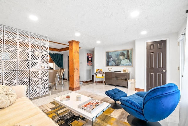 tiled living room featuring a textured ceiling and decorative columns