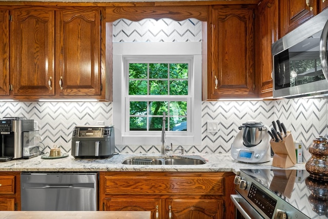 kitchen featuring tasteful backsplash, light stone counters, sink, and stainless steel appliances