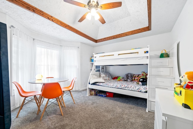 bedroom featuring a tray ceiling, ceiling fan, carpet, and a textured ceiling