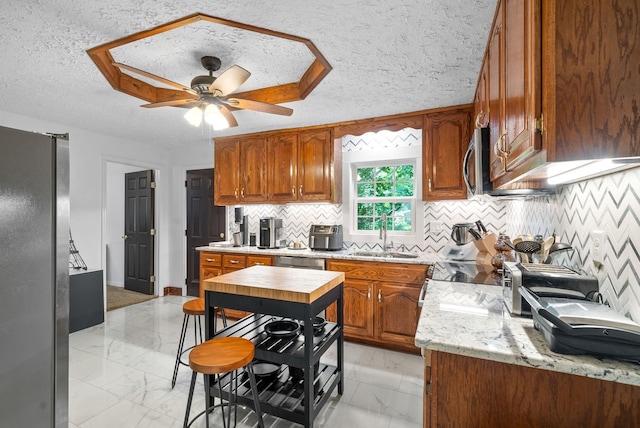 kitchen featuring a textured ceiling, ceiling fan, sink, and appliances with stainless steel finishes