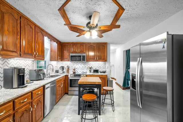 kitchen with wood counters, sink, a textured ceiling, and appliances with stainless steel finishes