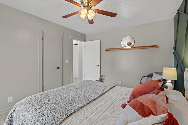 bedroom with ceiling fan, wood-type flooring, and a textured ceiling