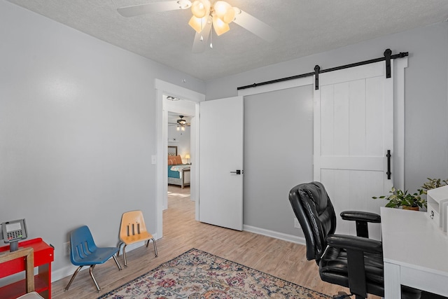 home office featuring a barn door, a textured ceiling, and light wood-type flooring