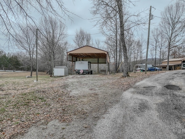 view of yard with a carport, an outbuilding, and driveway