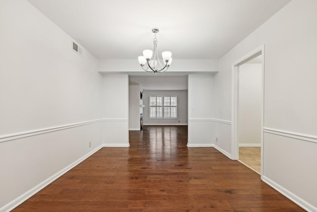 unfurnished dining area featuring dark wood-type flooring and a notable chandelier