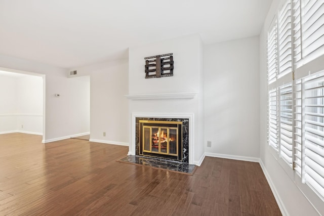 unfurnished living room with hardwood / wood-style floors, plenty of natural light, and a premium fireplace