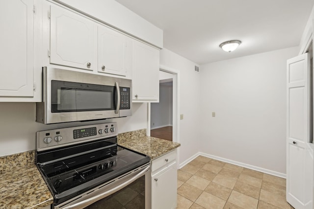 kitchen featuring white cabinets, stone countertops, light tile patterned flooring, and stainless steel appliances