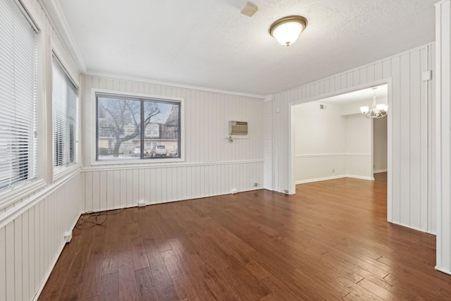 empty room featuring a textured ceiling, a chandelier, dark hardwood / wood-style floors, and ornamental molding