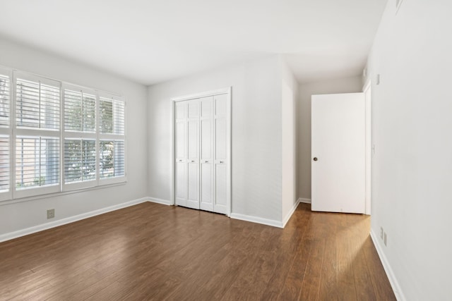 unfurnished bedroom with dark hardwood / wood-style flooring and a closet