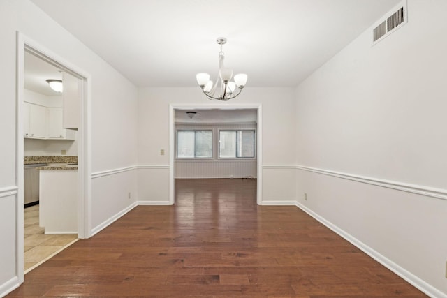 unfurnished dining area with a notable chandelier and dark hardwood / wood-style floors