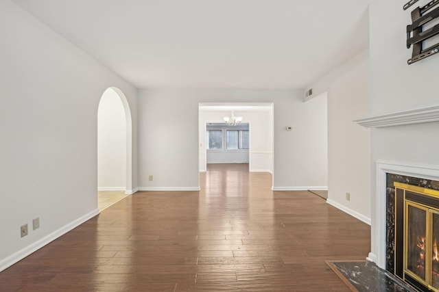 unfurnished living room featuring a high end fireplace, hardwood / wood-style floors, and a chandelier