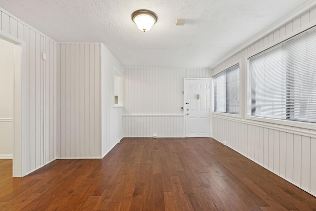 unfurnished room featuring dark hardwood / wood-style floors, a textured ceiling, and wooden walls