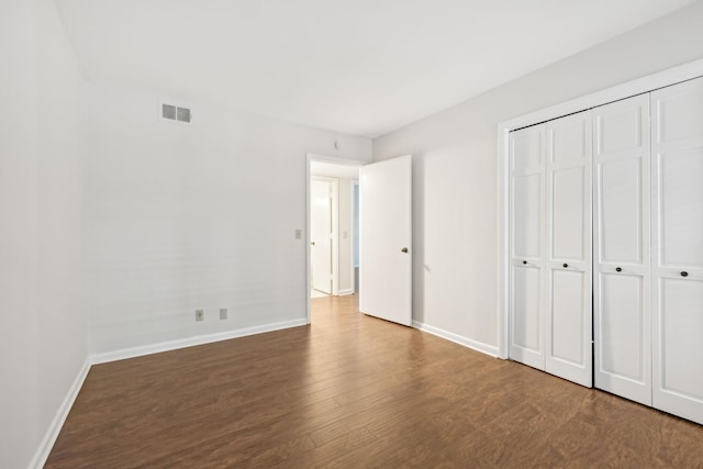 unfurnished bedroom with a closet and dark hardwood / wood-style floors