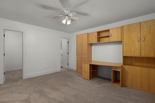 unfurnished bedroom with light carpet, built in desk, and ceiling fan