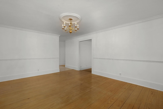 spare room with a chandelier, light wood-type flooring, and ornamental molding