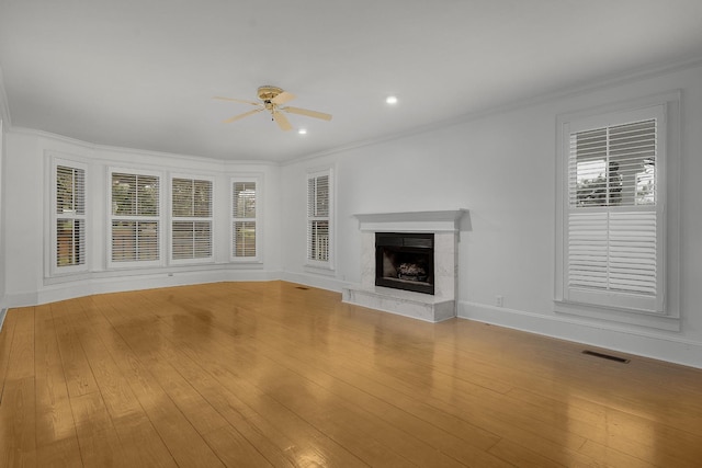 unfurnished living room featuring a fireplace, ceiling fan, light wood-type flooring, and ornamental molding