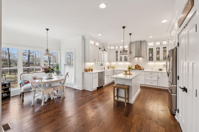 kitchen with white cabinets, wall chimney exhaust hood, a center island, and stainless steel appliances