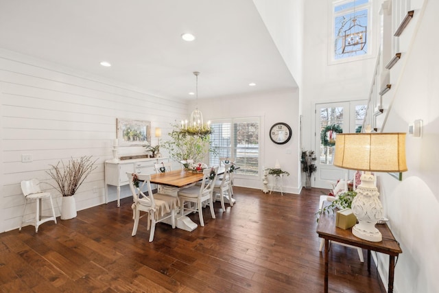 dining area featuring an inviting chandelier, dark wood-type flooring, and wood walls