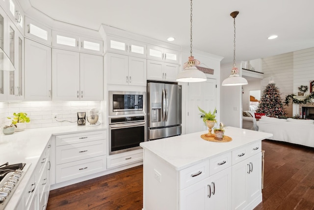 kitchen featuring white cabinets, appliances with stainless steel finishes, dark wood-type flooring, and pendant lighting