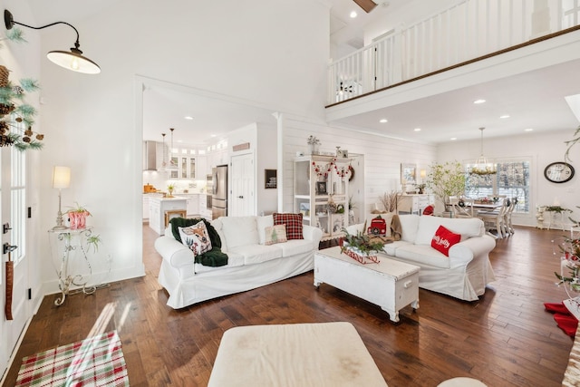 living room with a high ceiling, dark wood-type flooring, and wood walls