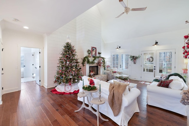 living room featuring ceiling fan, a large fireplace, french doors, dark wood-type flooring, and high vaulted ceiling