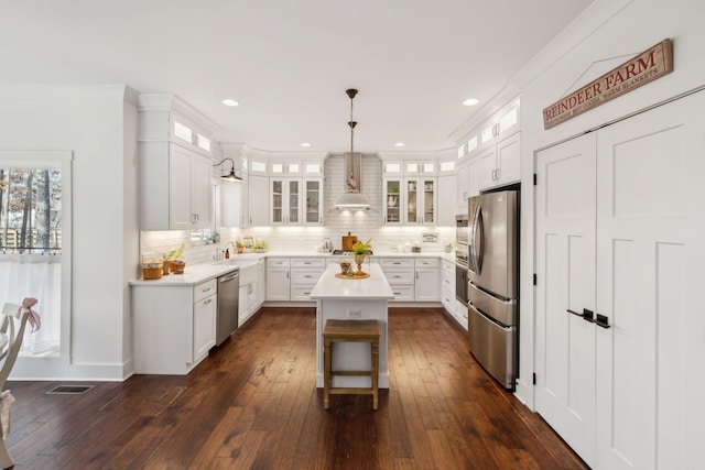 kitchen featuring white cabinets, decorative light fixtures, a center island, and stainless steel appliances