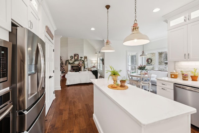 kitchen with a center island, hanging light fixtures, dark wood-type flooring, stainless steel appliances, and white cabinets