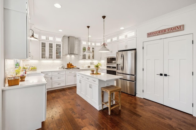 kitchen featuring white cabinets, wall chimney exhaust hood, a kitchen island, and stainless steel appliances