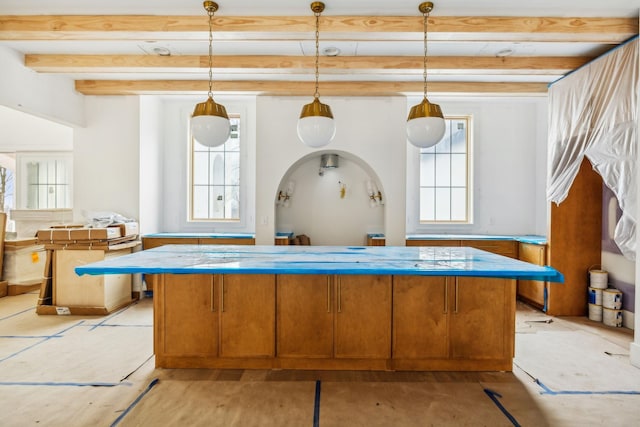 kitchen featuring pendant lighting, beam ceiling, and a wealth of natural light