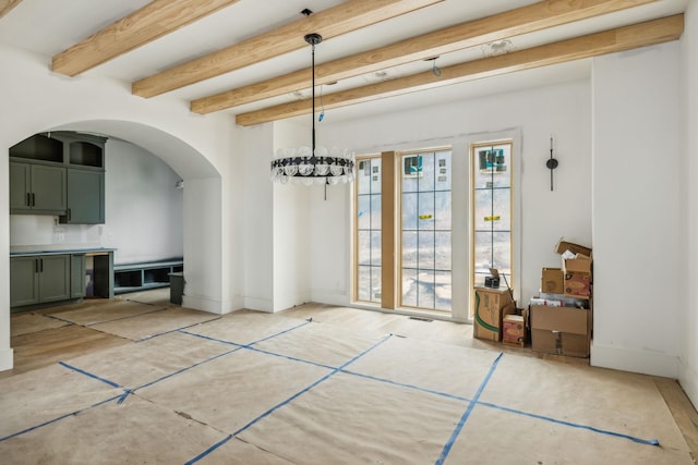 unfurnished dining area with beamed ceiling and a chandelier