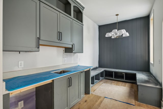 kitchen with a notable chandelier, gray cabinets, hanging light fixtures, and light hardwood / wood-style flooring