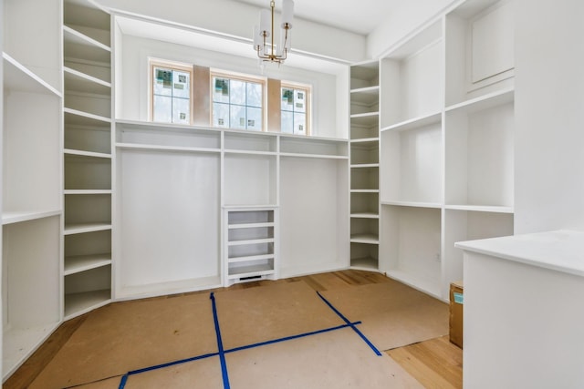 walk in closet with hardwood / wood-style floors and a chandelier